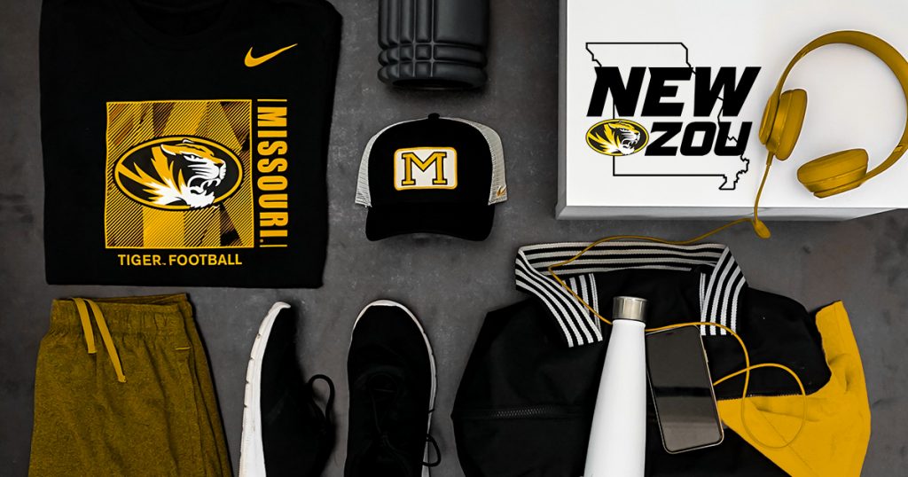 Top-down look at black and gold apparel products with Mizzou marks. T-shirt, hat, pants, shoes, headphones.
