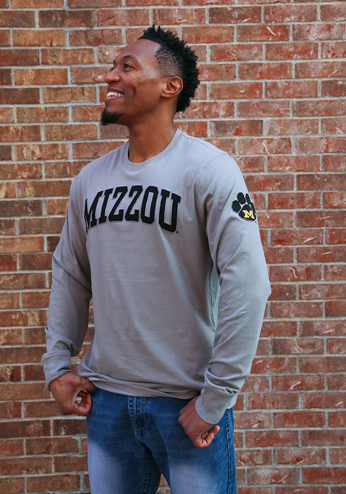Man wearing gray sweatshirt with Mizzou wordmark on chest and Tiger M vintage mark on sleeve.