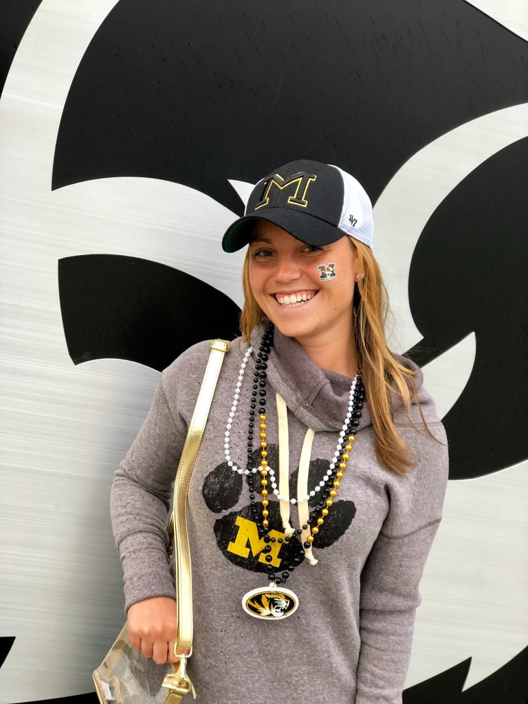 Woman smiling at camera wearing hoody with vintage mark.